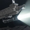 Olight weapon mounted flashlight emitting bright beam from rifle rail mount