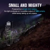 Olight I3T compact flashlight side view with pocket clip, 180 lumens illuminating a dark rocky trail.