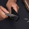 Man's hands using small screwdriver on black electronic device.