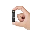 Hand holding a compact black Olight EDC keychain flashlight.