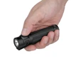 Hand holding a black flashlight with green button