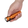 Hand holding an orange flashlight with a textured grip, black clip, and side button against a white background.
