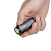 Olight Silver Baton 4 Premium flashlight held in hand, side view, textured body with black and gold accents for everyday carry.