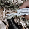 Person using a NexTool multi-tool bottle opener to open a glass bottle outdoors