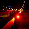 Red warning lights on a metal bridge railing at night with blurred city street lights in the background