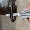 Person using the metal file tool of a stainless steel pocket multitool on a rusty iron loop