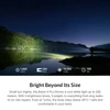Night scene, person with bright flashlight on lake shore, powerful beam across water, trees illuminated on far bank.