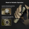 Gloved hand holding green tactical flashlight with textured tail switch and hexagonal side button details.