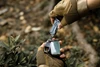 Gloved hands using a Nextool pocket multitool screwdriver to open a car key fob outdoors