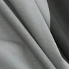Close-up of a draped, light olive green knit fabric with distinct vertical ribs