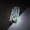 NexTool compact multi-tool with glowing green light on dark textured surface