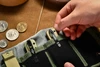 Hand placing an Oknife folding pocket knife with a black clip into a green canvas EDC organizer pouch