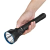 Olight Black Javelot Turbo 2 flashlight held in hand with blue bezel for long-range tactical use.