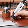 HOZO NeoBlade ultrasonic cutting knife slicing through brown leather on a cutting mat in a workshop
