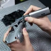 Using HOZO ultrasonic cutting knife to trim silver plastic model car body on grid cutting mat
