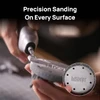 Close-up of a person using an electric rotary pen tool to sand and polish a small 3D-printed miniature base.