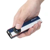 Hand holding Olight Arkfeld flat EDC flashlight in blue, white, and red color scheme with thumb on central power button