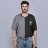 Man in a gray and black split tee, blue jeans, and a watch.