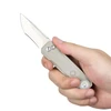 Hand holding a beige folding knife with a light, white background