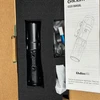 Olight Black Odin Mini tactical flashlight in foam packaging with user manual for weapon-mounted illumination