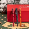 Three colorful pens on Christmas cards with a red gift box and snowy Christmas trees.