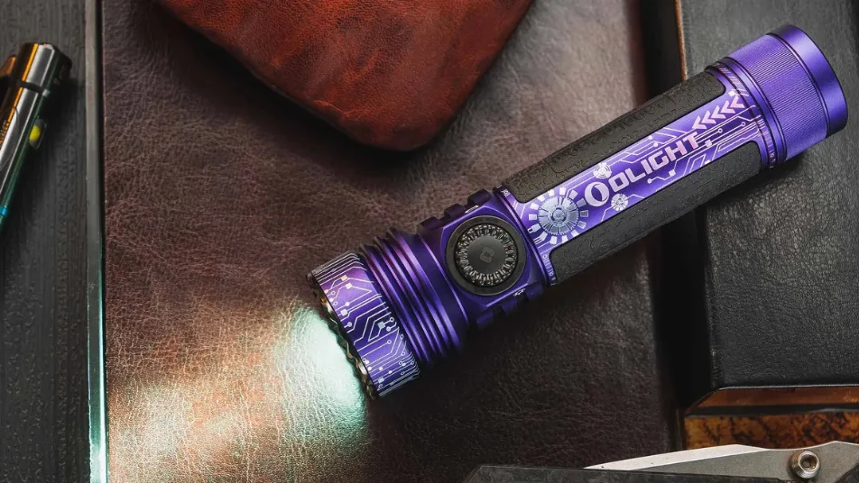 Purple Olight flashlight with circuit board design shining on a dark leather surface. EDC gear.