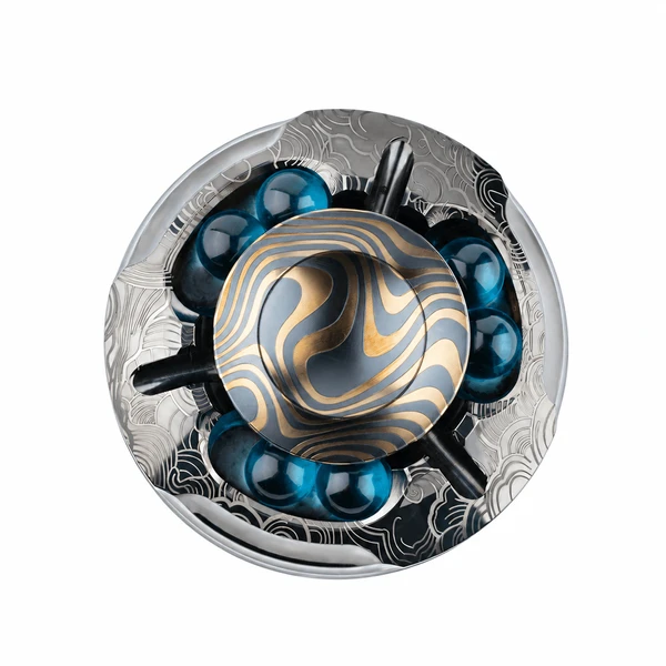 Intricate metal mechanical device with gold wavy patterns and blue glass spheres on white background