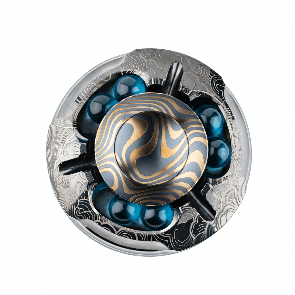 Modern round metallic sculpture with gold wave patterns, engraved silver base, and blue glass spheres on white background