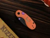Kizer orange Halloween pocket knife with jack-o-lantern face cutouts on wooden background