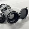 Tactical thermal imaging scope with open flip cap on a grey surface