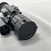 Black tactical thermal rifle scope with protective lens cap on gray background